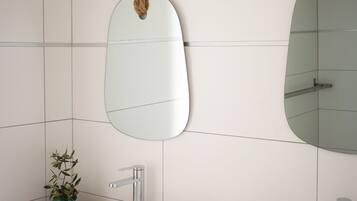 A modern bathroom with two white sinks, a wooden vanity, and a mirror with a rope decoration.