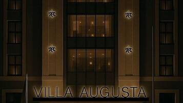 Un hotel llamado 'Villa Augusta' de estilo arquitectónico clásico, con una entrada destacada y amplias ventanas.