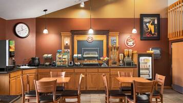 A kitchen area with wooden cabinets, a clock, a coffee machine, and a refrigerator.