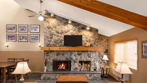 A cozy living room with a stone fireplace, a flat-screen TV mounted above it, and a comfortable seating area with a sofa and a coffee table. - AmericInn by Wyndham Detroit Lakes (Detroit Lakes)