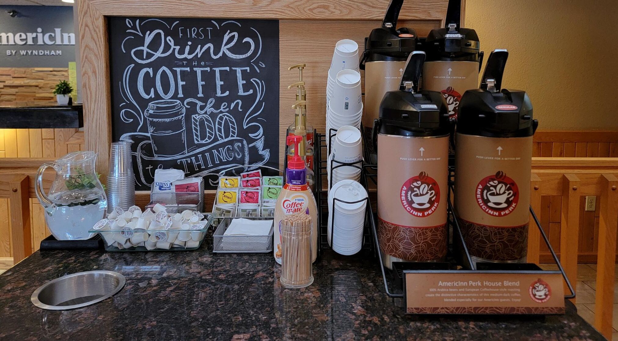 Angolo caffè con lavagna, macchine da caffè, tazze e cartello che indica la miscela di caffè.