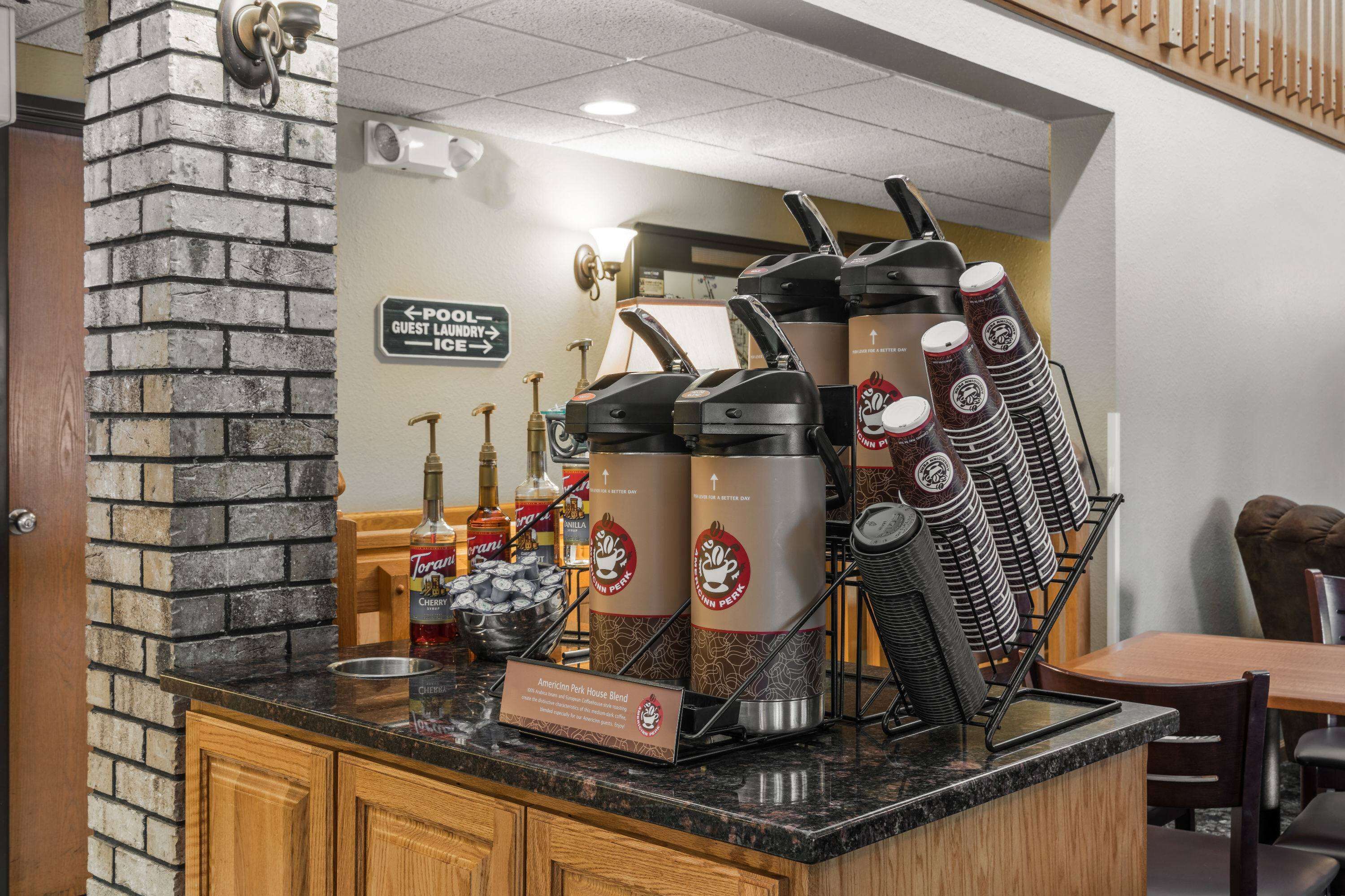 A coffee station with multiple coffee dispensers, a sign indicating a guest laundry area, and a variety of condiments and beverages.