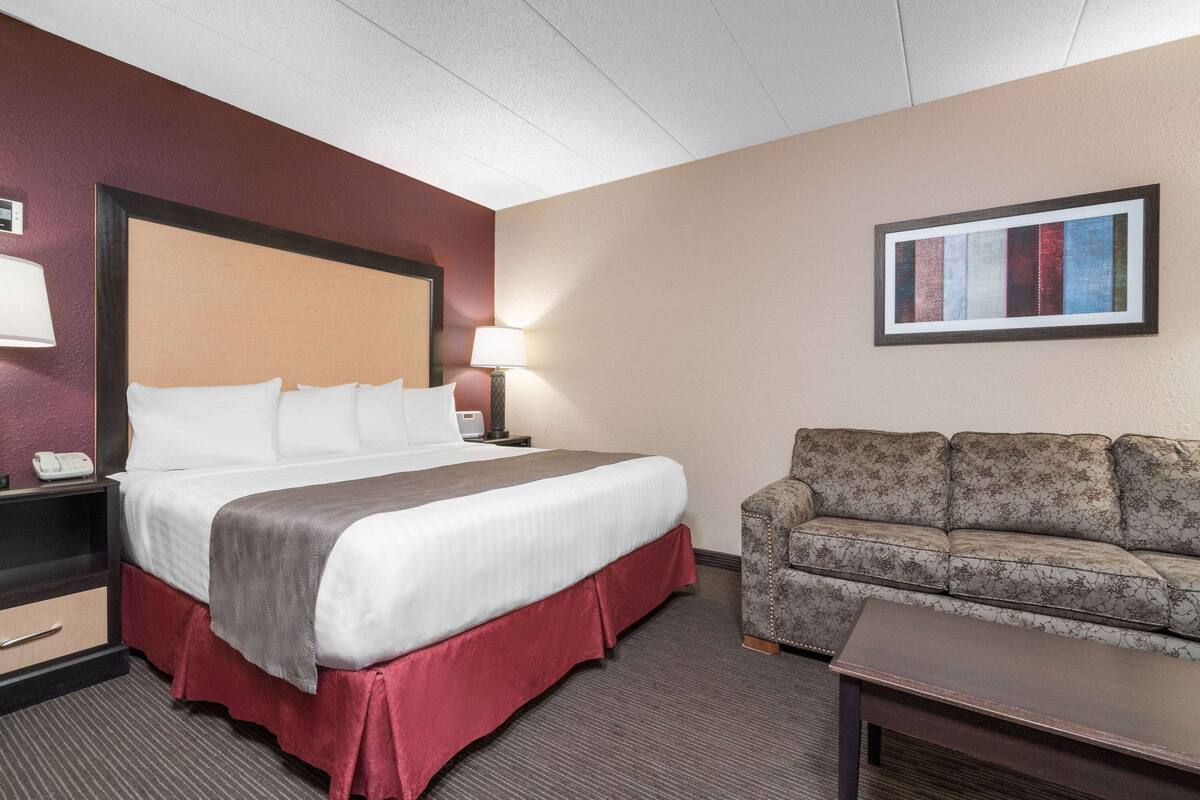 Ein Hotelzimmer mit einem großen Bett, einer Couch, einem Schreibtisch und einem gerahmten Bild an der Wand.