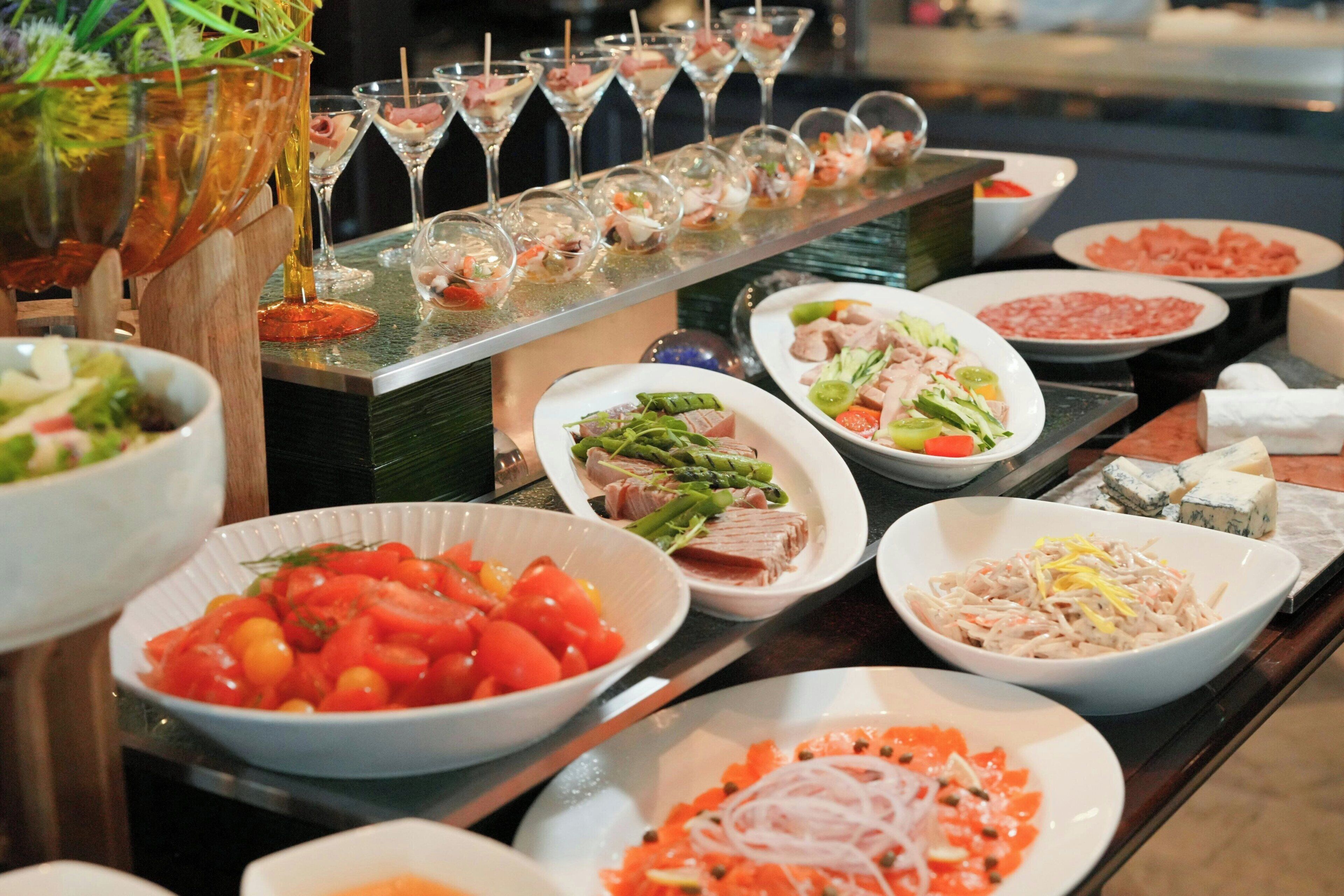 A buffet with various dishes and a selection of glasses.