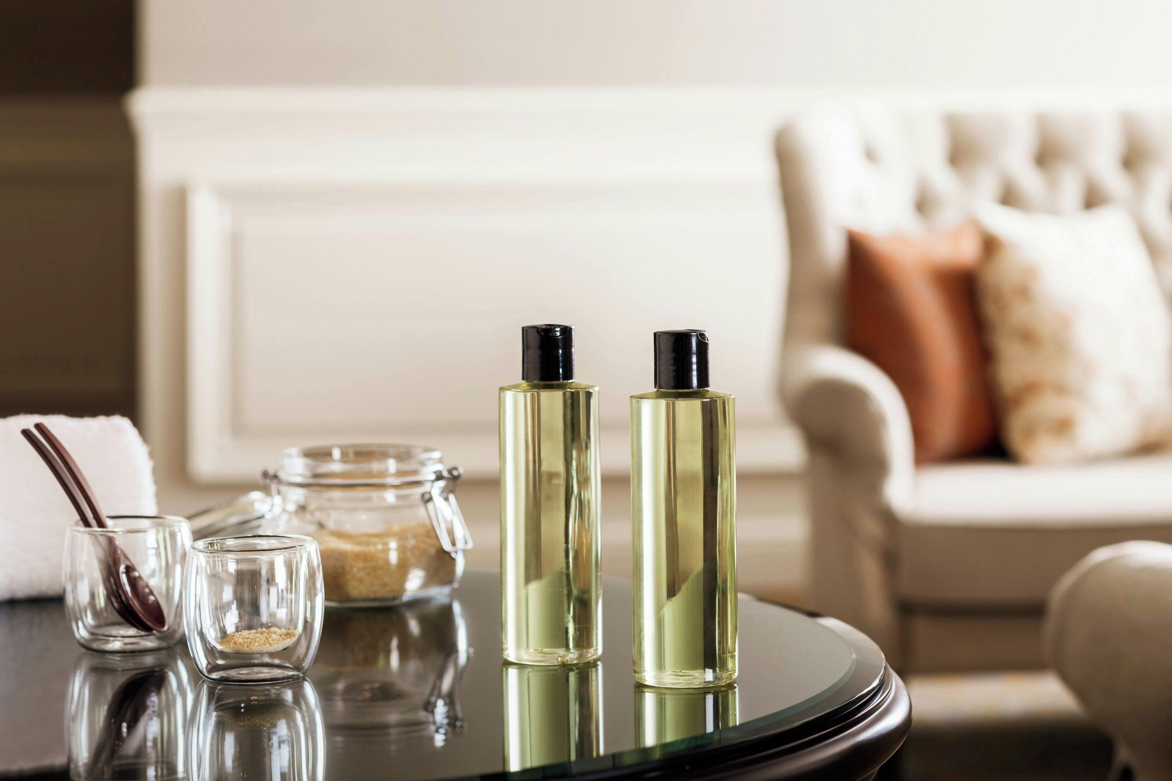 A table with two perfume bottles, a glass jar, and a spoon.