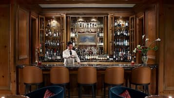 A bar area with a bartender, wooden paneling, and a variety of liquor bottles.