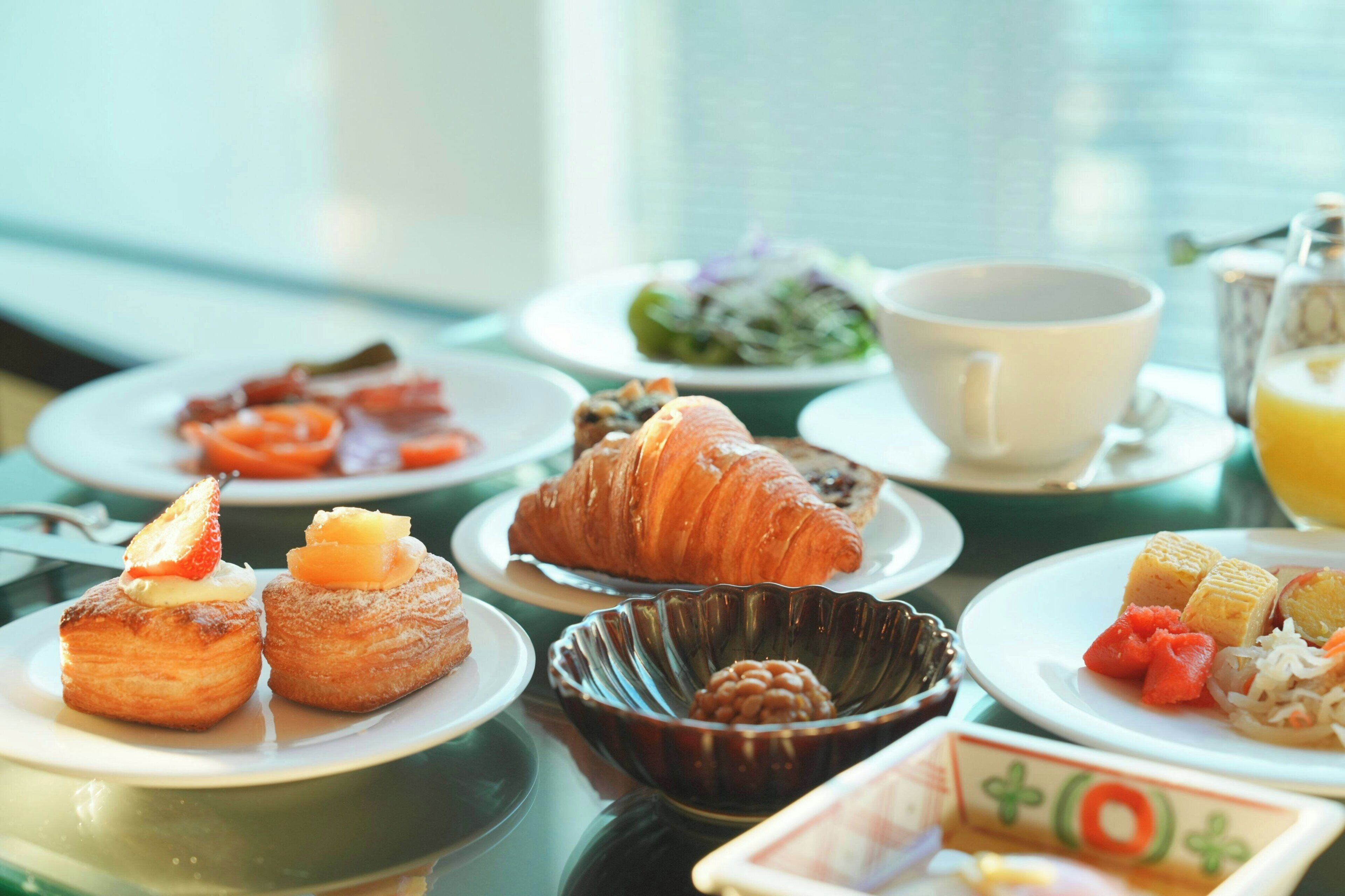 Una escena de desayuno con pasteles, una taza y un plato de comida sobre una mesa.
