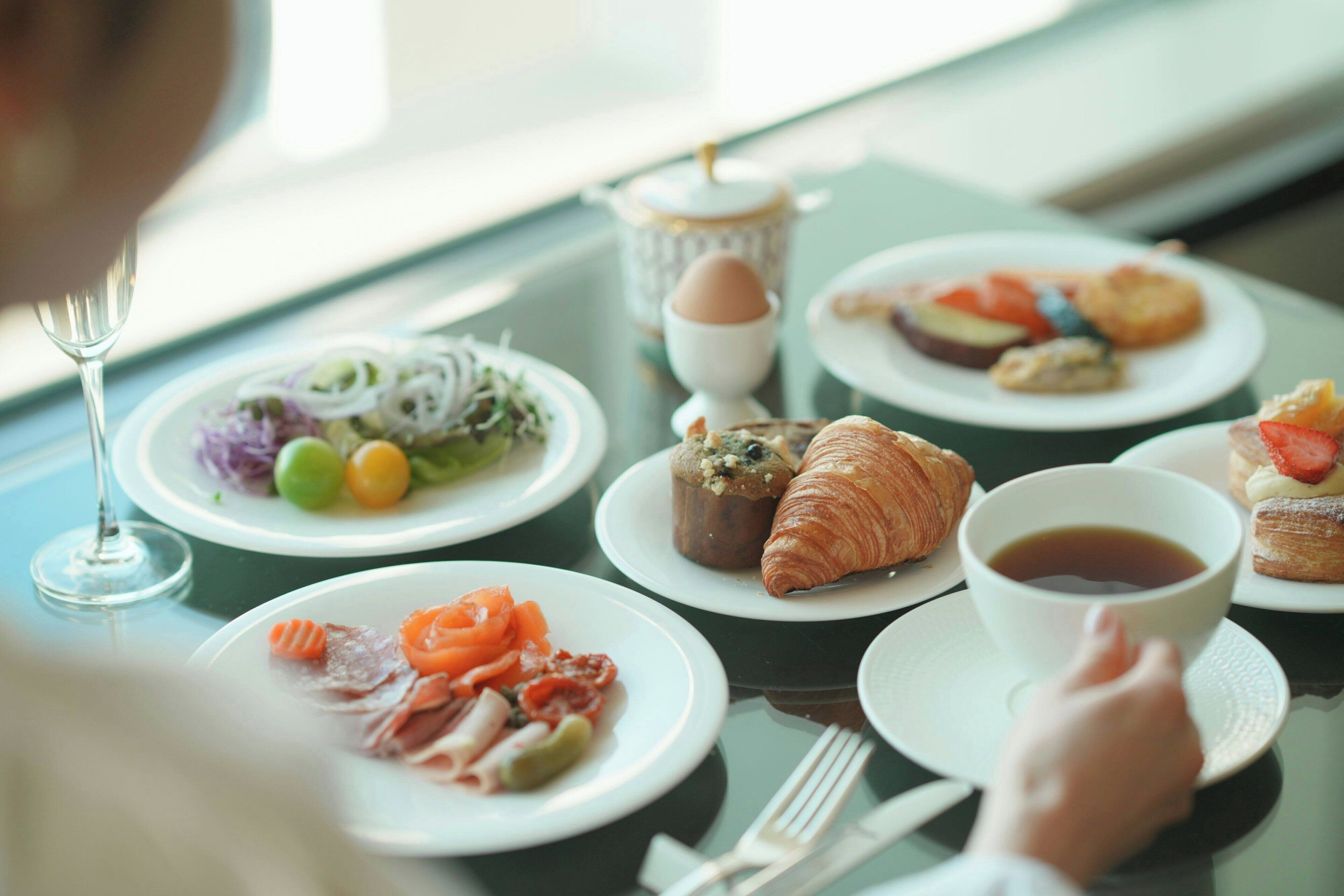 Una escena de desayuno con platos de comida, una taza de té y un vaso de agua sobre una mesa.