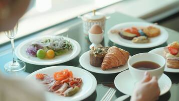 Una escena de desayuno con platos de comida, una taza de té y un vaso de agua sobre una mesa.
