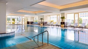 An indoor swimming pool with clear blue water, sunlit by large windows, and surrounded by lounge chairs and potted plants. - The Ritz-Carlton, Osaka (Osaka)