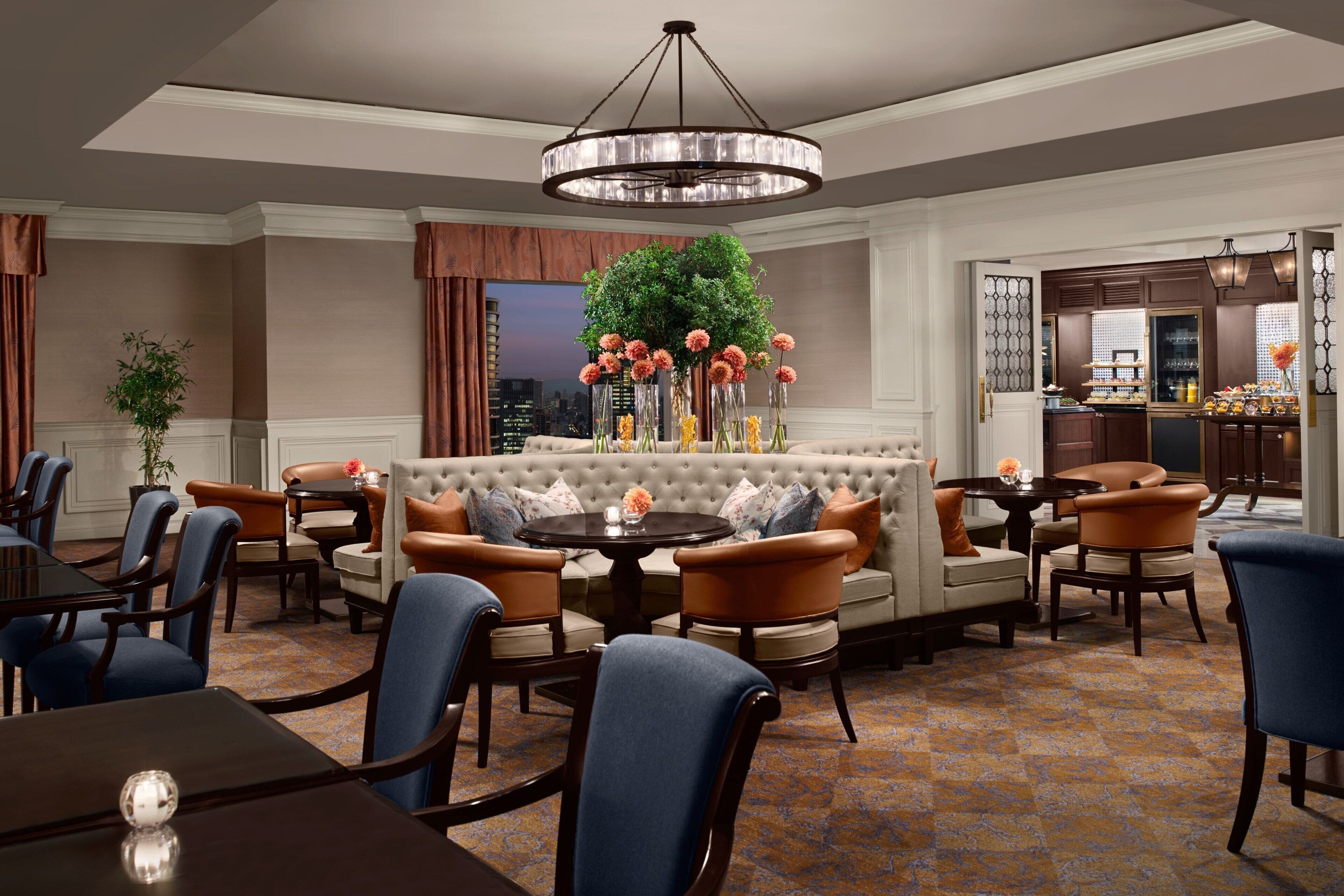 A hotel lobby with a round table, sofas, and chairs arranged around it.