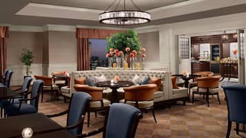 A hotel lobby with a round table, sofas, and chairs arranged around it.