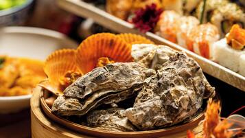 Diversos pratos de frutos do mar, incluindo ostras e camarões, apresentados numa cesta de madeira.