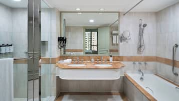 Un baño moderno con cabina de ducha de vidrio, tocador doble, bañera y un espejo grande.