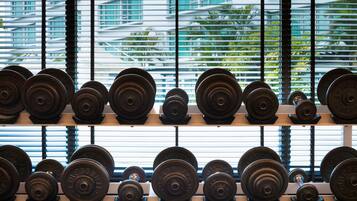 A row of weight plates on a rack, with a window in the background.