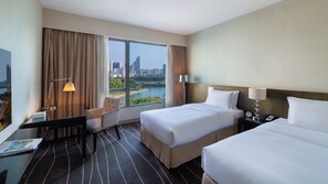 A hotel room with two beds, a desk, a chair, and a view of a cityscape and river. - Marco Polo Xiamen (Xiamen)