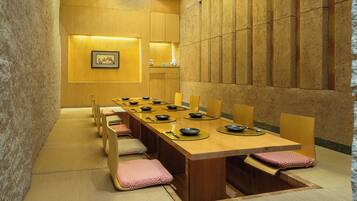 A traditional Japanese-style dining room with a long wooden table, tatami mats, and low wooden chairs.