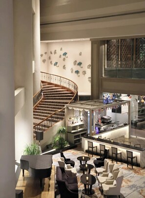 A hotel lobby with a spiral staircase, seating area, bar, and decorative wall art. - Marco Polo Xiamen (Xiamen)