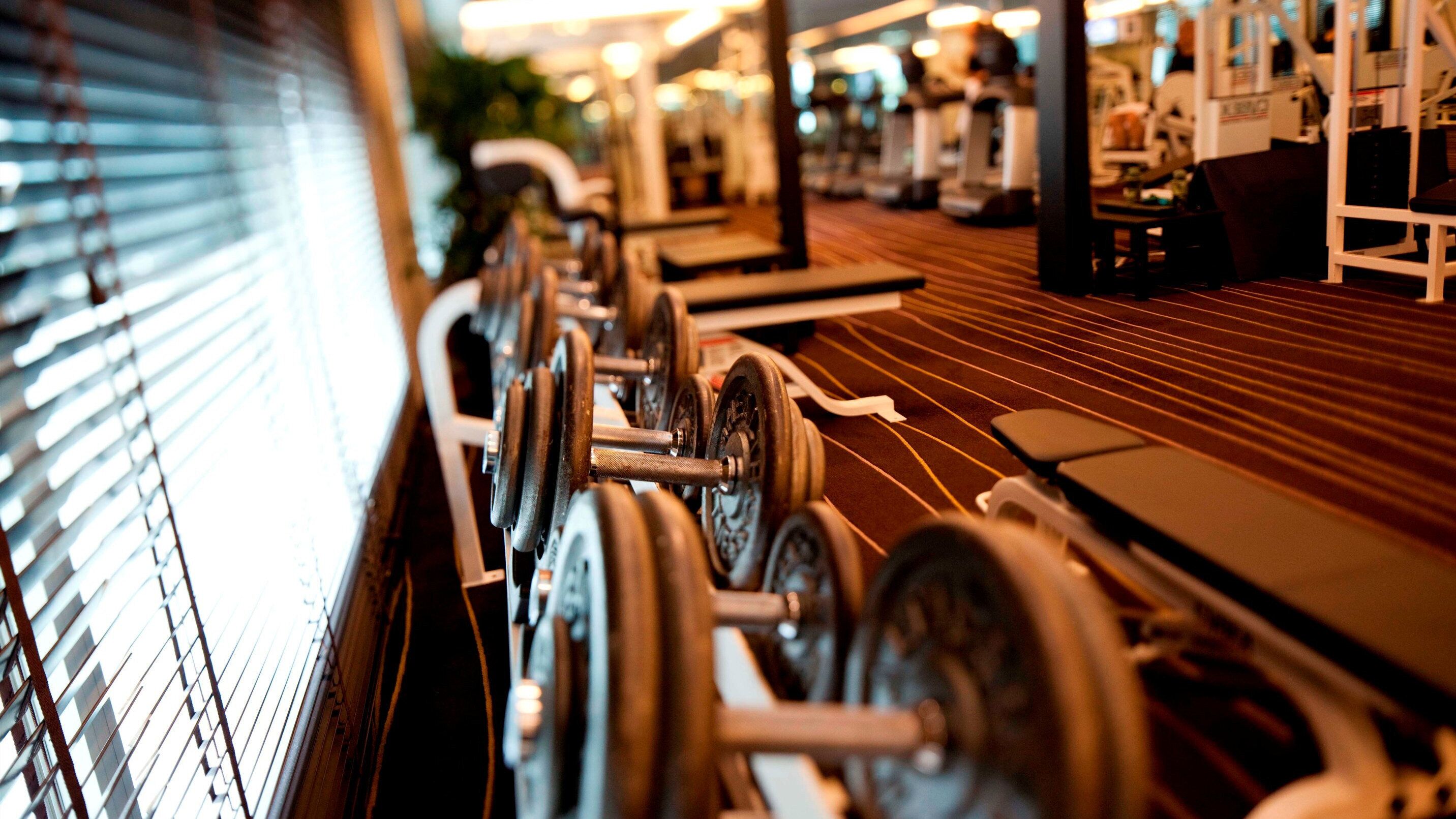 A gym with exercise equipment, including dumbbells and treadmills.