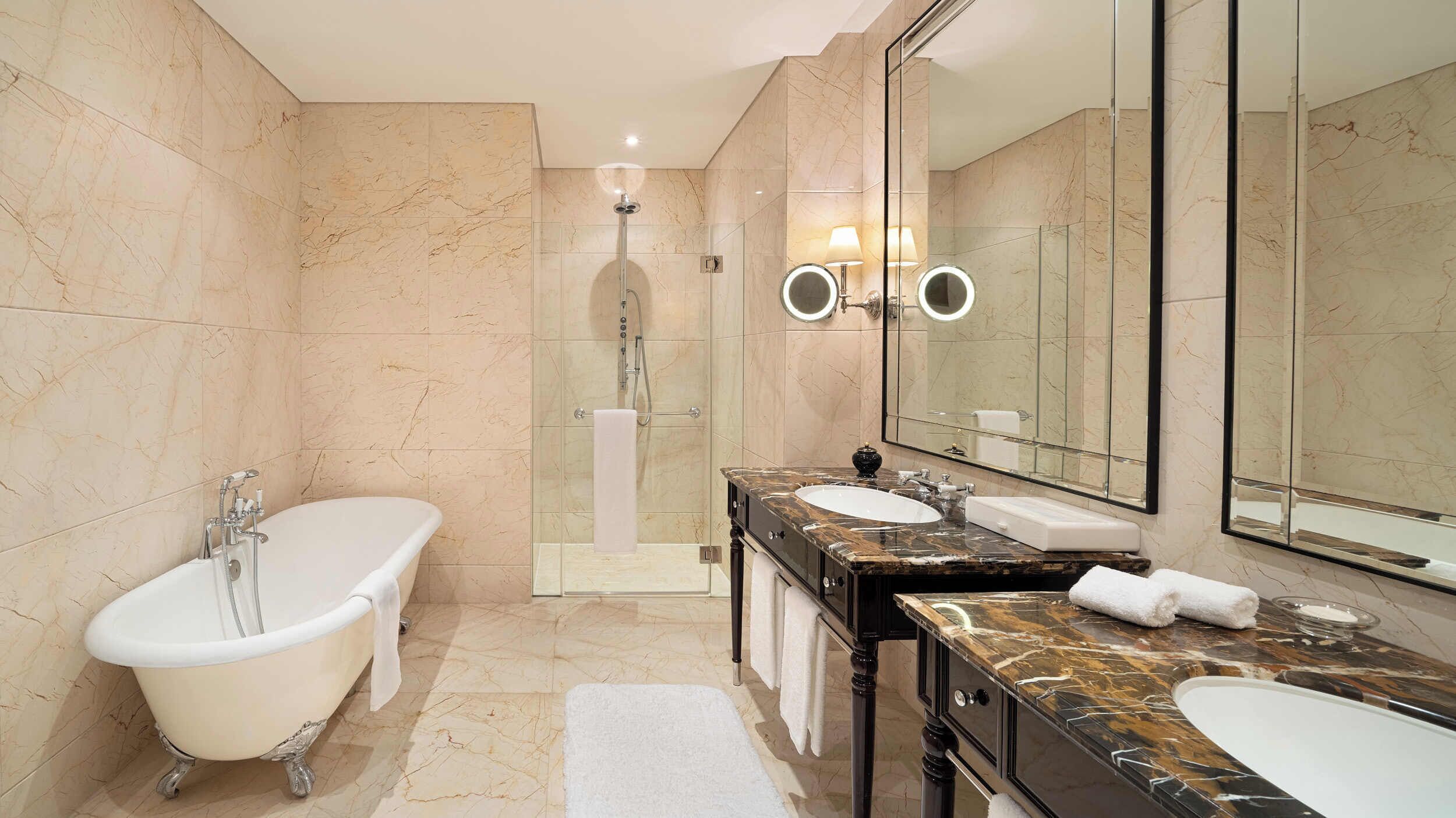 A modern bathroom with a freestanding bathtub, two sinks, a large mirror, and a glass-enclosed shower area.