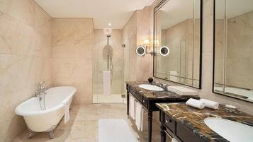A modern bathroom with a freestanding bathtub, two sinks, a large mirror, and a glass-enclosed shower area.
