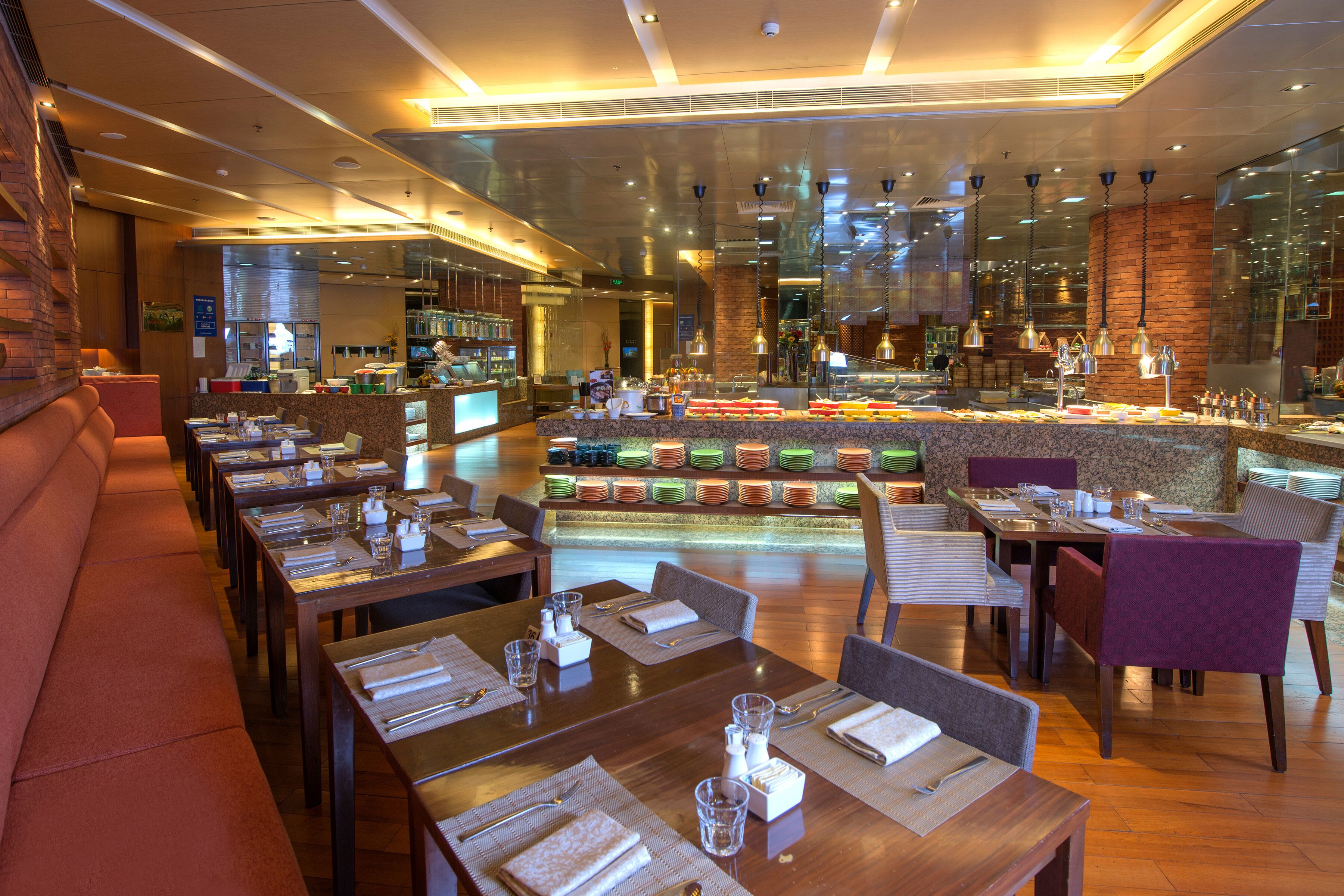 Ein Restaurant mit mehreren Tischen, Sitzecken, einer Bar und einer Theke, an der verschiedene Gerichte präsentiert werden.