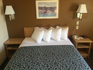A hotel room with a bed, two nightstands, a painting on the wall, and a patterned bedspread. - Days Inn by Wyndham Hurricane/Zion National Park Area (Hurricane)