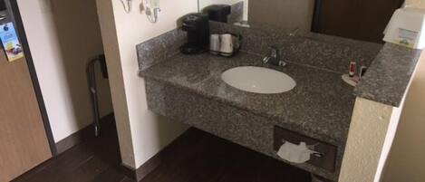 A bathroom with a granite countertop, a sink, a towel rack, and a mirror.