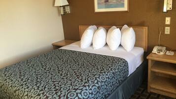 A hotel room with a bed, a nightstand, a telephone, and a painting on the wall.