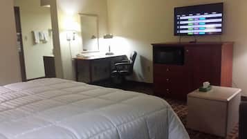 A hotel room with a bed, a desk with a chair, a television, and a small cabinet.