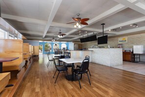 A spacious dining area with wooden tables and chairs, ceiling fans, and a Daybreak Breakfast sign. - Days Inn by Wyndham Fort Myers Springs Resort (Fort Myers)