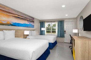 A hotel room with two beds, a large painting, a desk, a chair, and a TV. - Days Inn by Wyndham Fort Myers Springs Resort (Fort Myers)