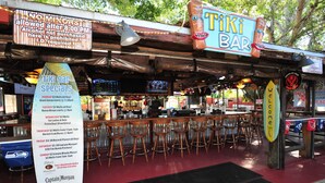 A tiki bar with a wooden exterior, multiple seating areas, and a menu board advertising specials. - Days Inn by Wyndham Fort Myers Springs Resort (Fort Myers)
