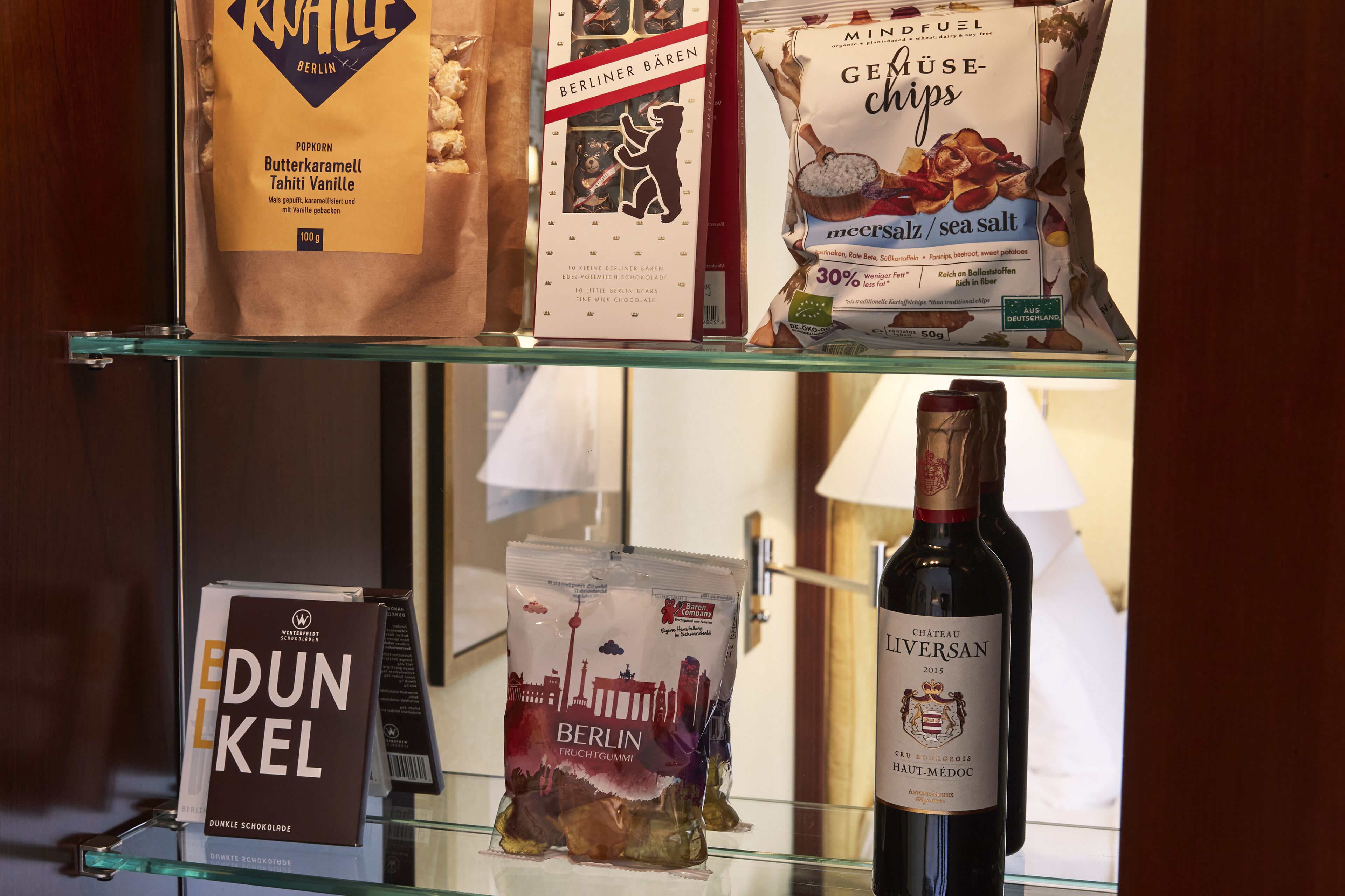 A display of snacks and a bottle of wine on a shelf.