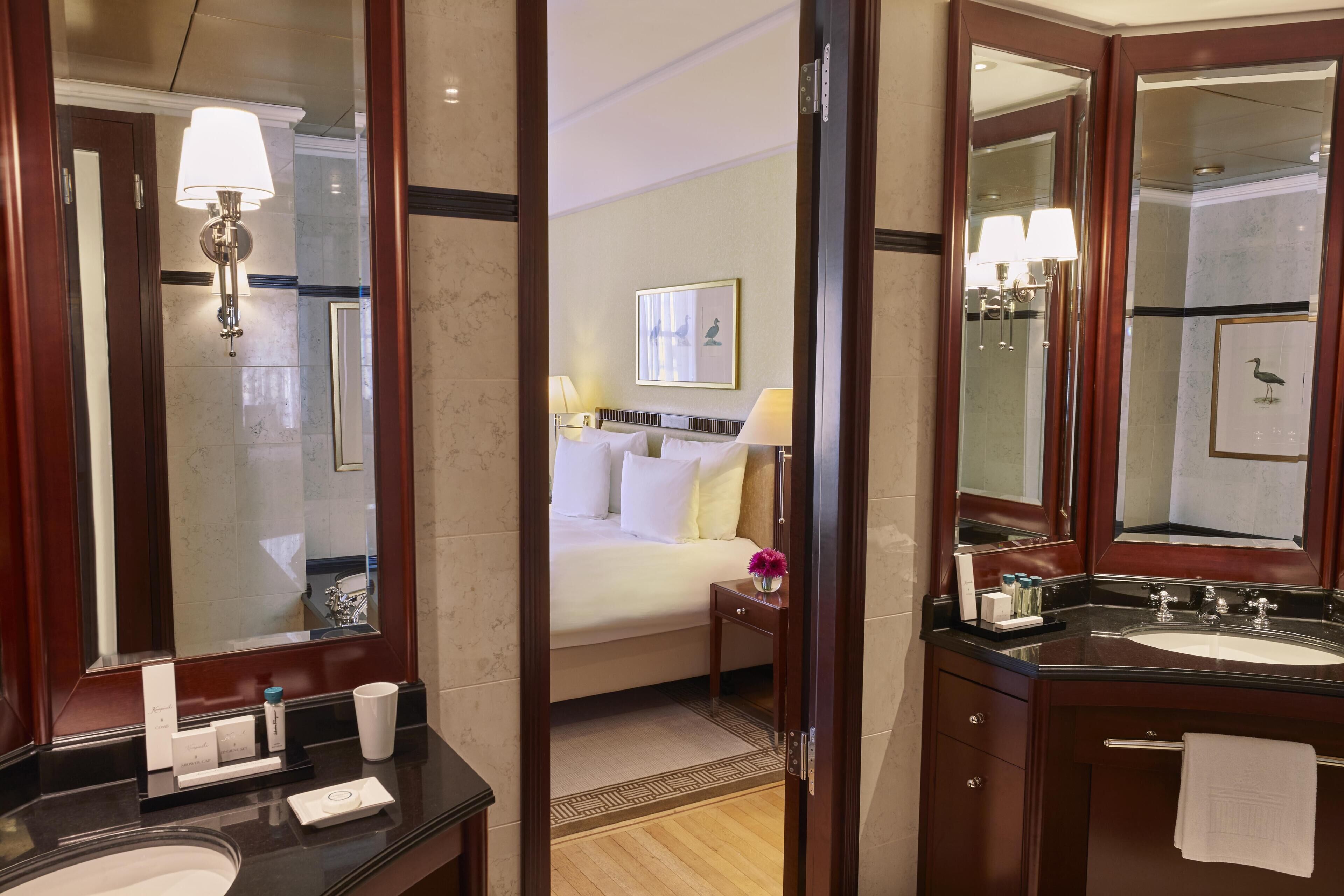 A hotel bathroom with a large mirror, a sink, and a shower area.