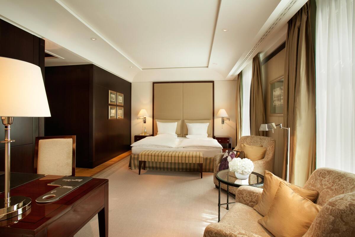 A hotel room with a bed, a desk, a chair, and a sofa.