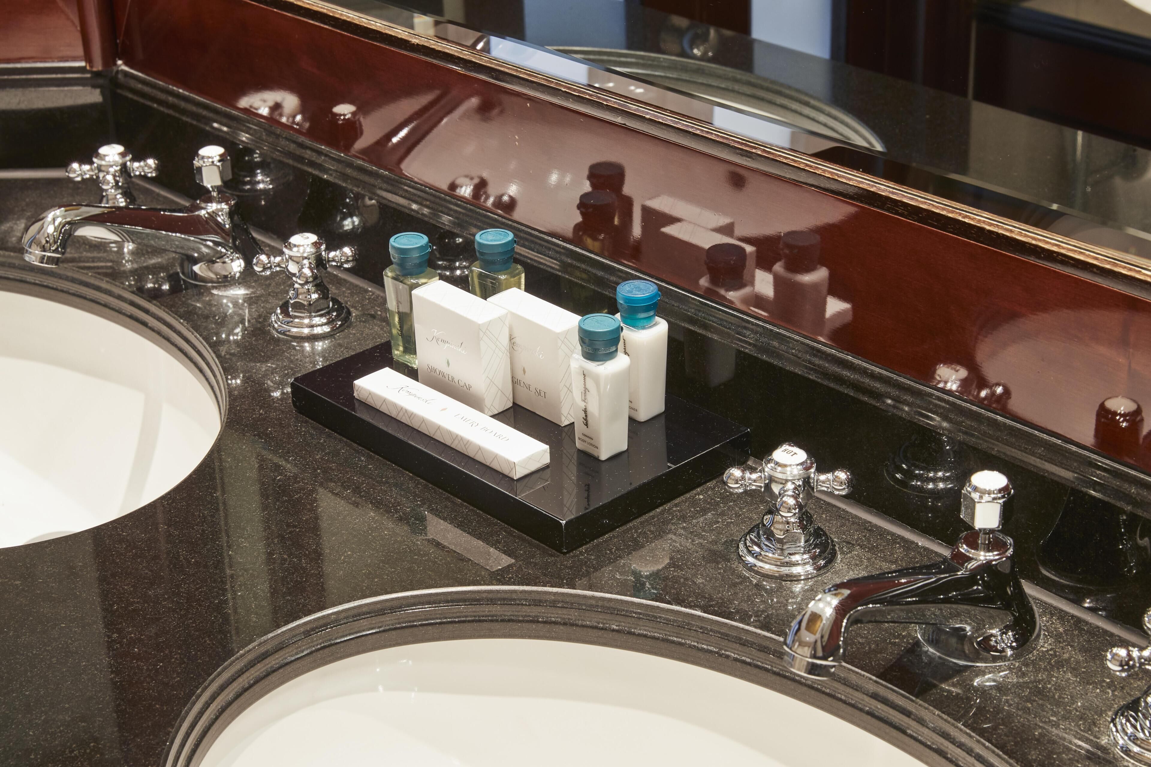 A bathroom with two sinks, a mirror, and a black tray holding toiletries.