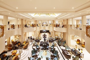 A spacious hotel lobby with multiple seating areas, a central fountain, and a high ceiling with skylights. - Hotel Adlon Kempinski (Berlin)