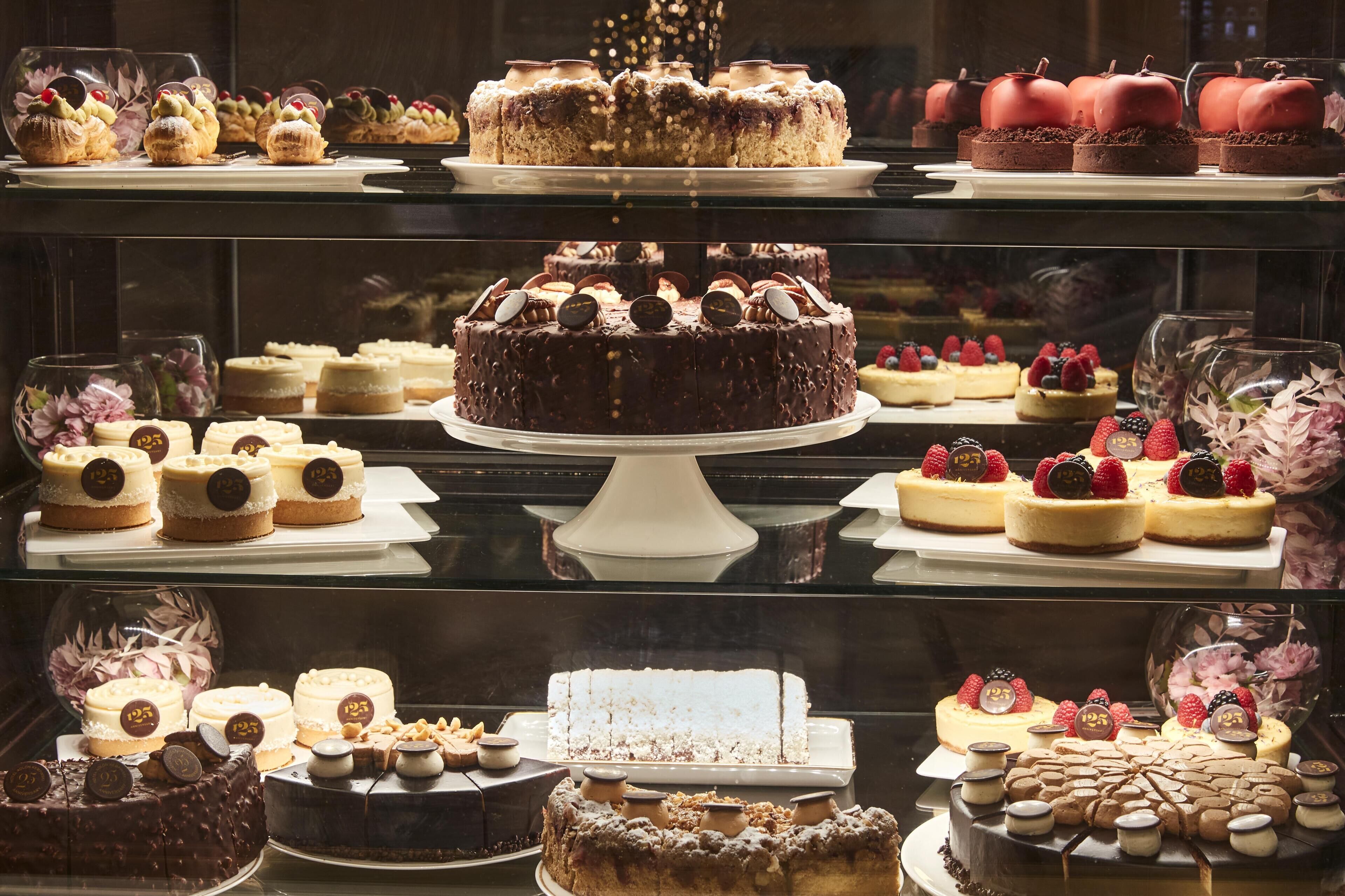Una variedad de postres expuestos en una vitrina, incluyendo pasteles y repostería.