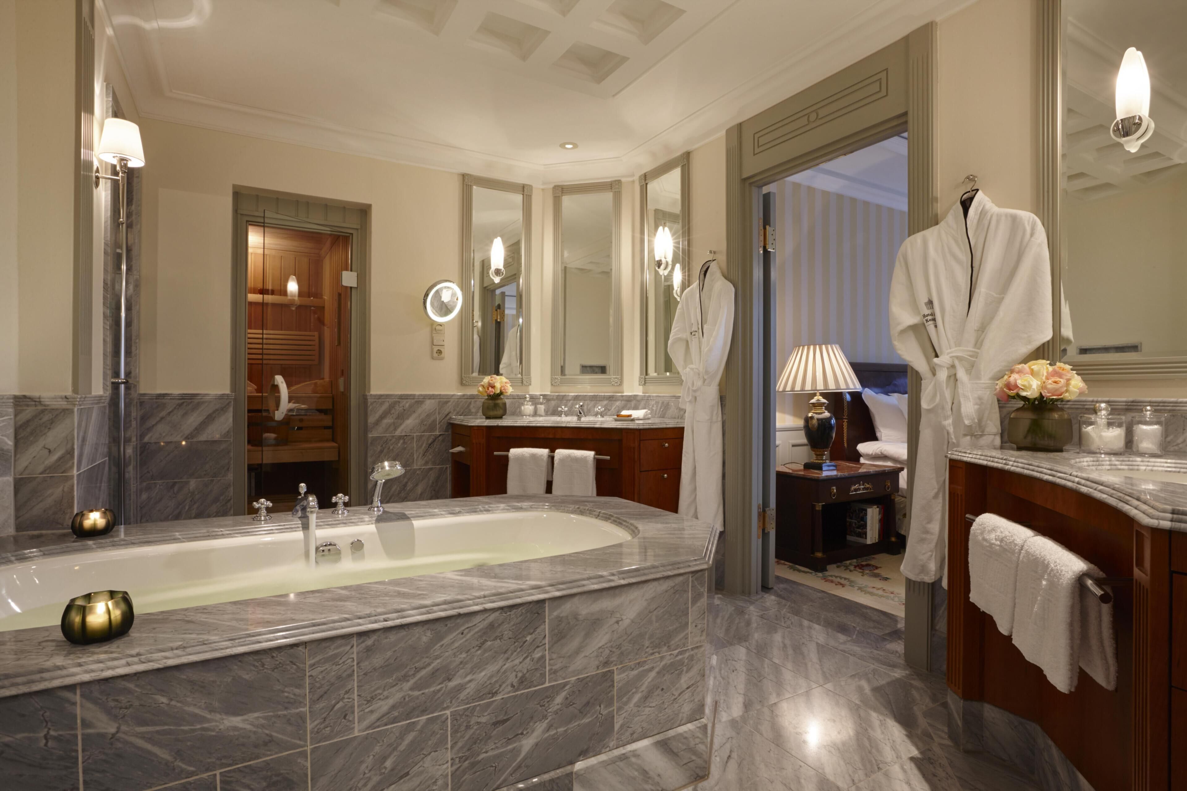 A spacious bathroom with a large bathtub, a vanity with a mirror, and a robe hanging on the wall.