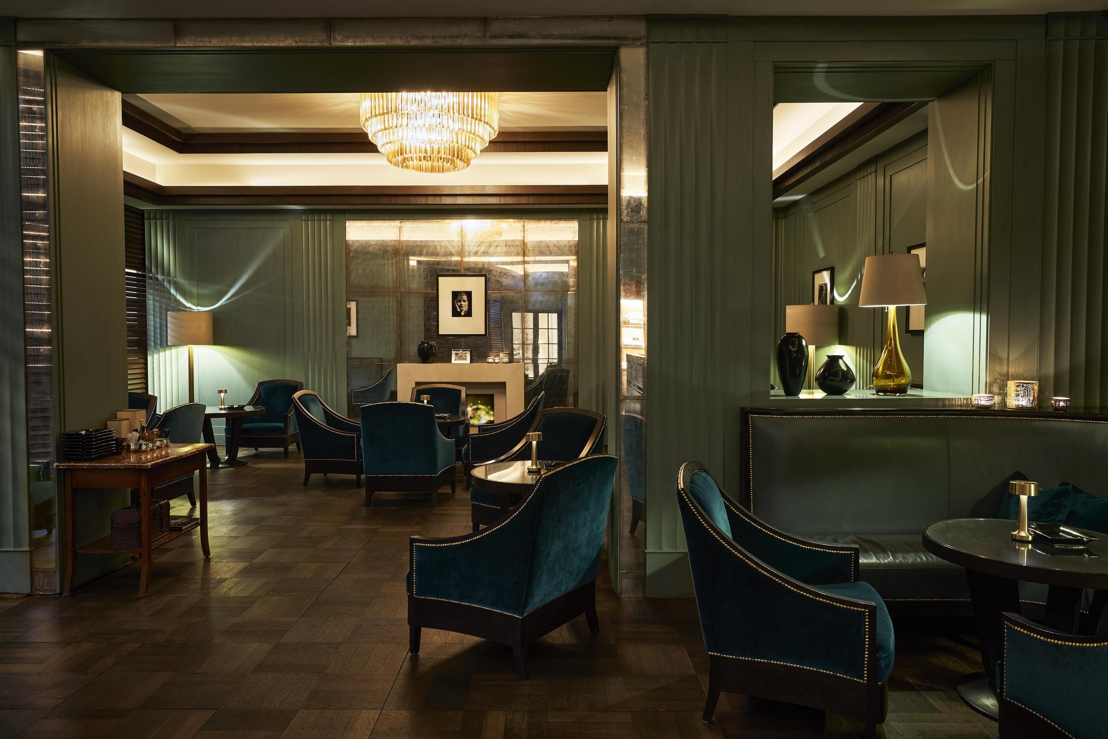 A hotel lobby with a chandelier, seating area, and a fireplace.