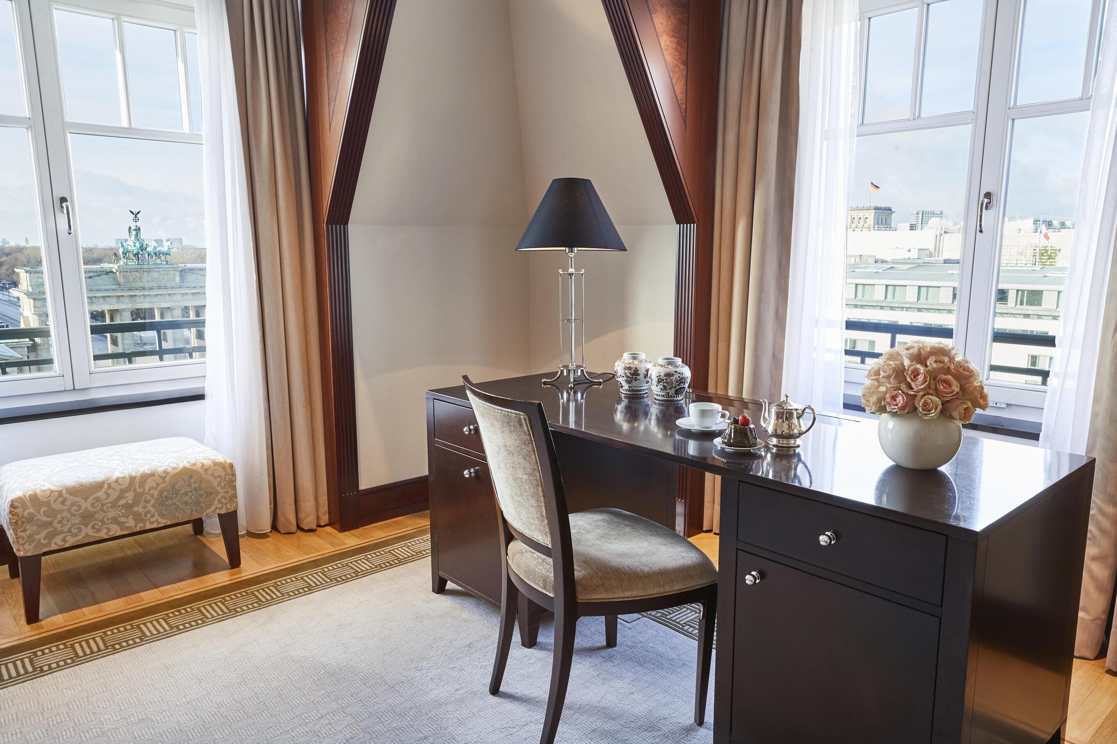 A hotel room with a desk, chair, and a view of the cityscape.