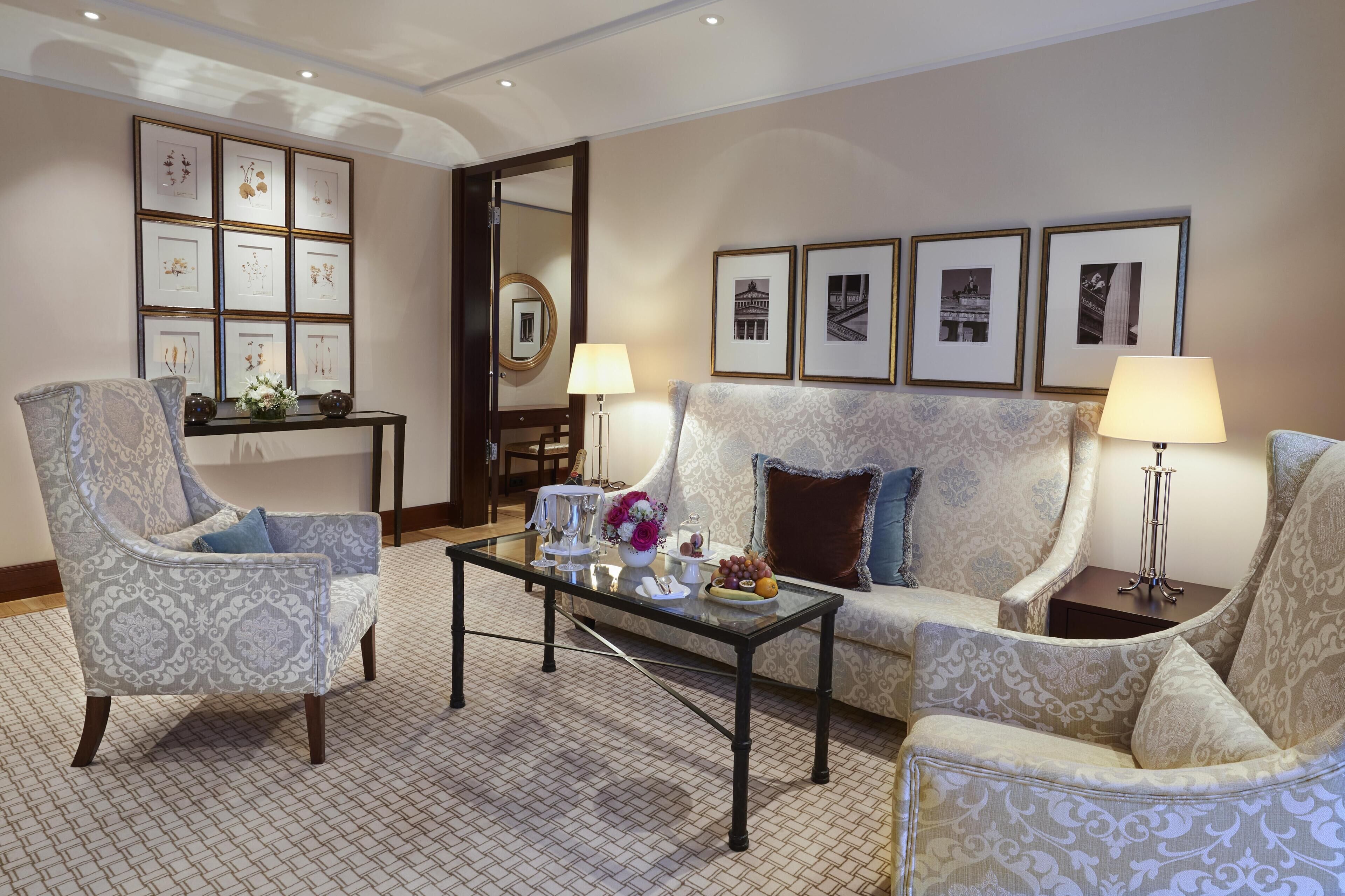 A well-appointed living room with a sofa, armchairs, a coffee table, and framed artwork on the walls.