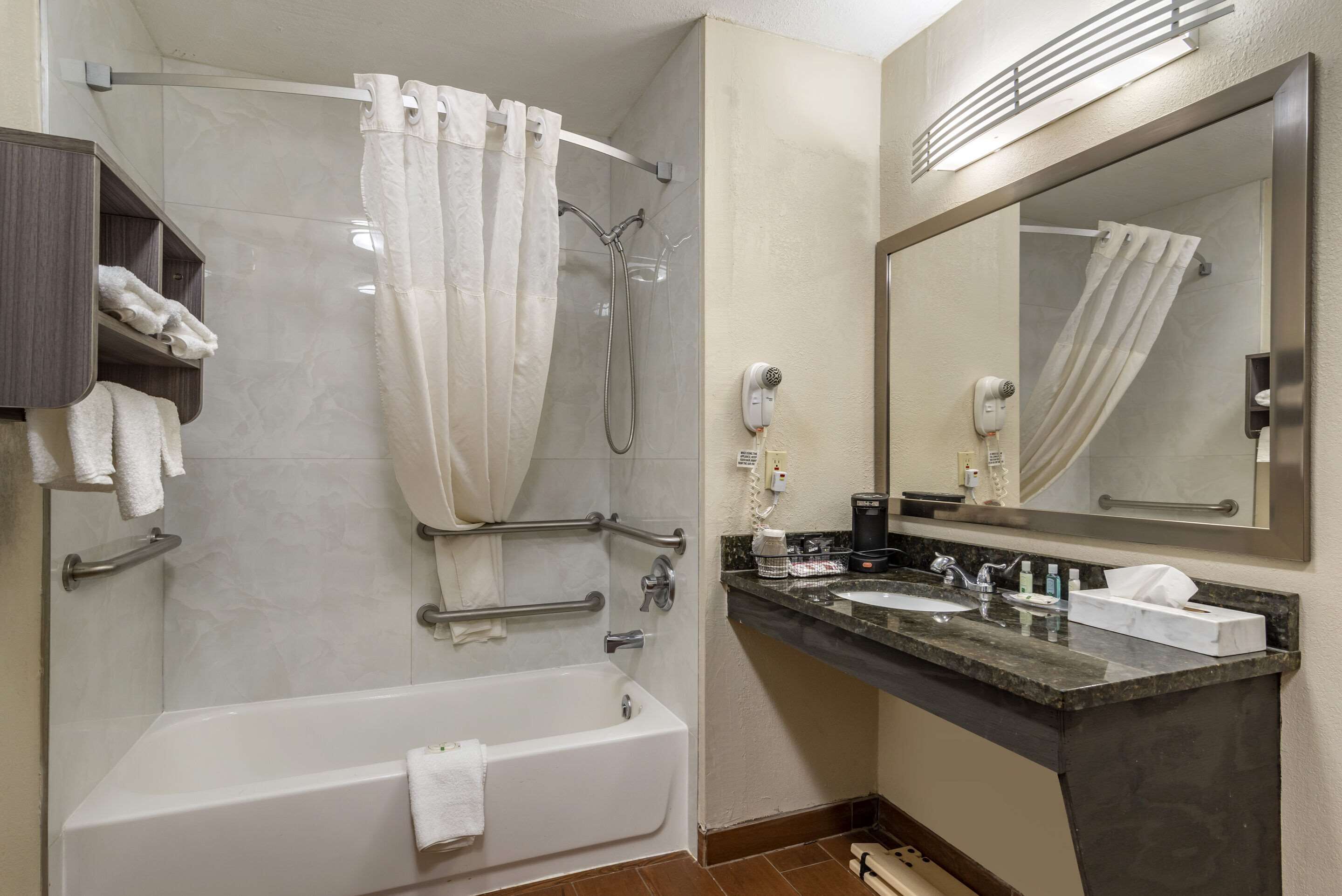 A modern bathroom with a bathtub, shower, vanity with a sink, and a large mirror.