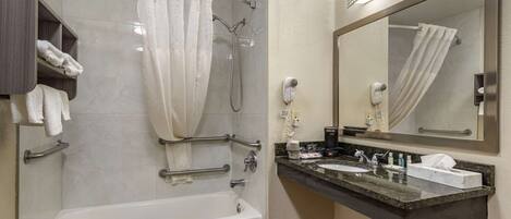 A modern bathroom with a bathtub, shower, vanity with a sink, and a large mirror.