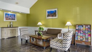 Een woonkamer met een groene wand, twee fauteuils, een bank, een bijzettafeltje en een tijdschriftenrek.
