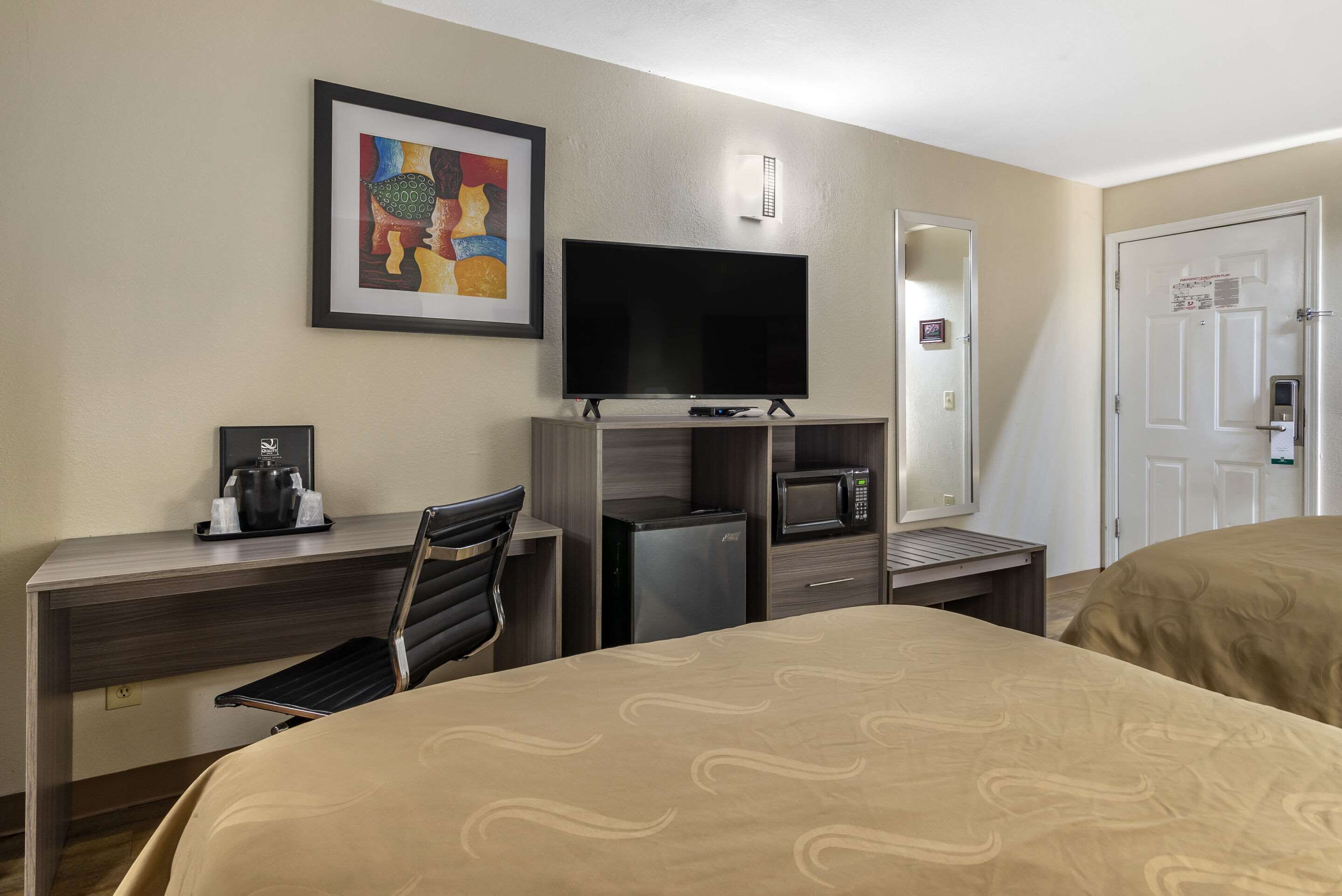 Een hotelkamer met een bed, een bureau met een flatscreen televisie, een magnetron, een koelkast en een koffiezetapparaat.