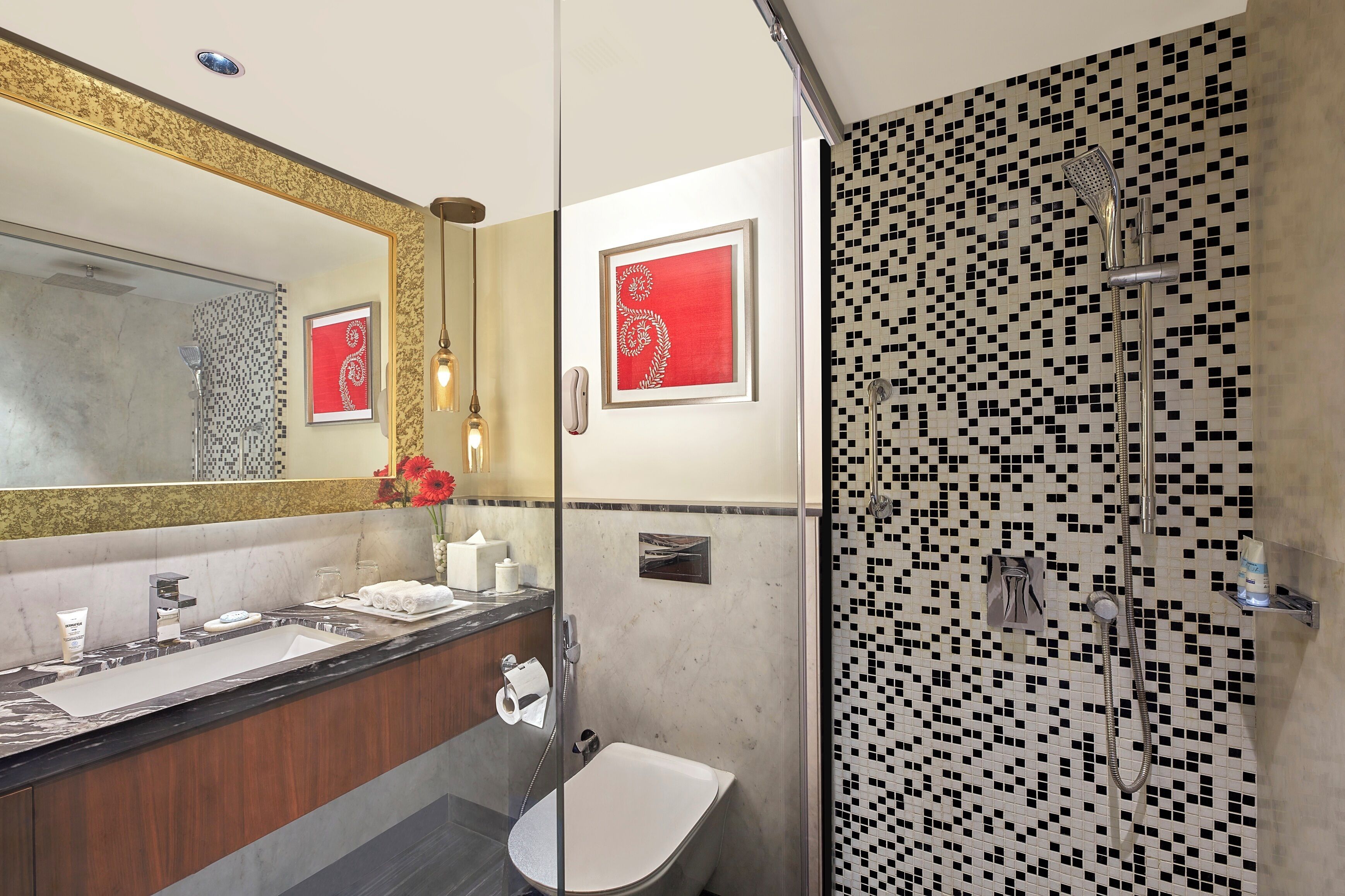 A modern bathroom with a large mirror, two sinks, a shower, and a toilet.