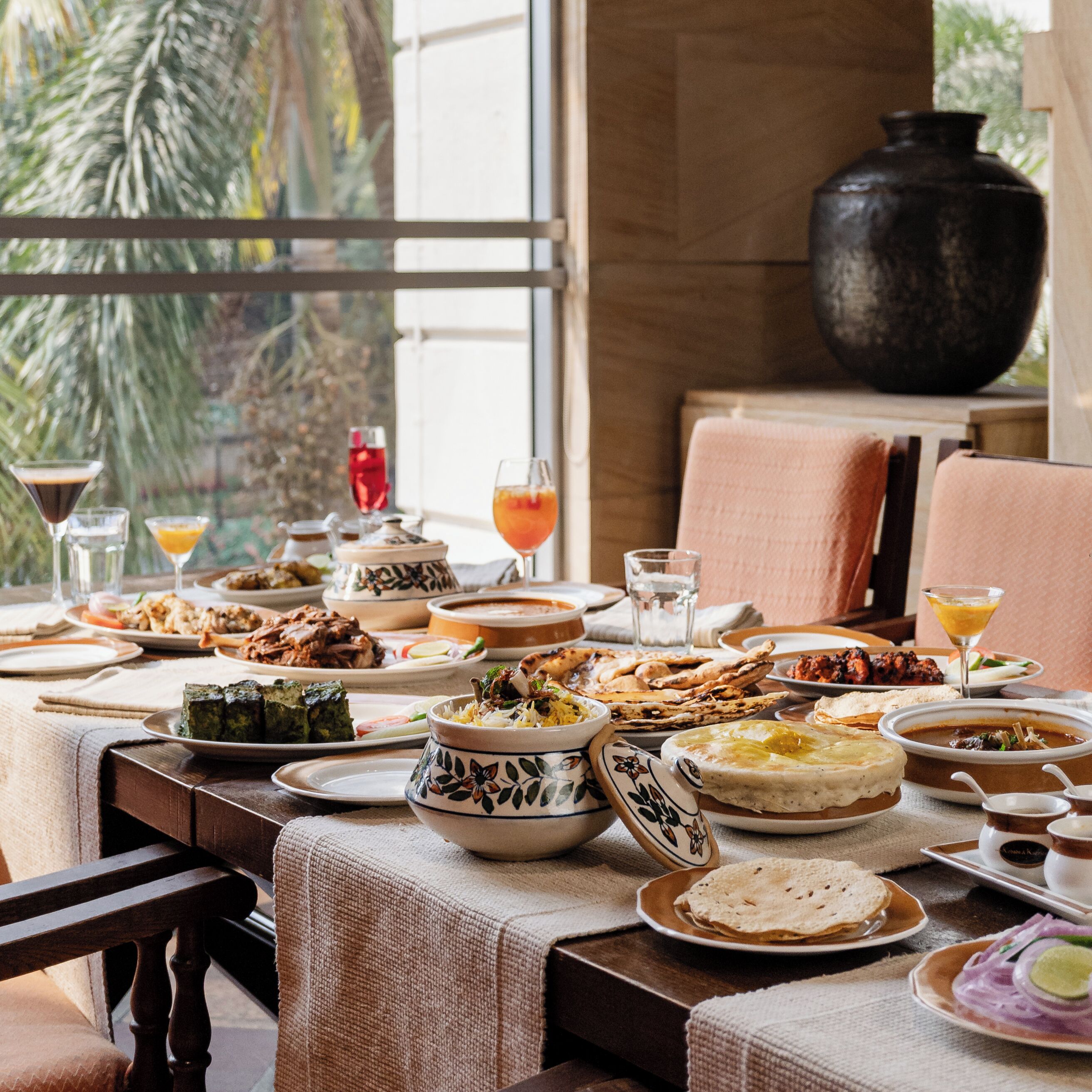 A dining table set with various dishes, glasses, and a large black vase.