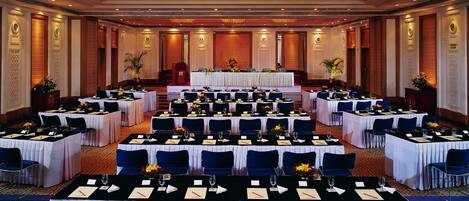 Un salón de banquetes con mesas redondas, manteles blancos y sillas azules.
